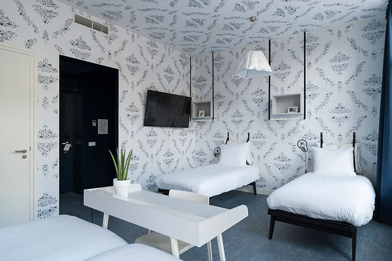 Lichte kamer met tweepersoonsbed en twee eenpersoonsbedden, bureau en tv | Kaboom Hotel