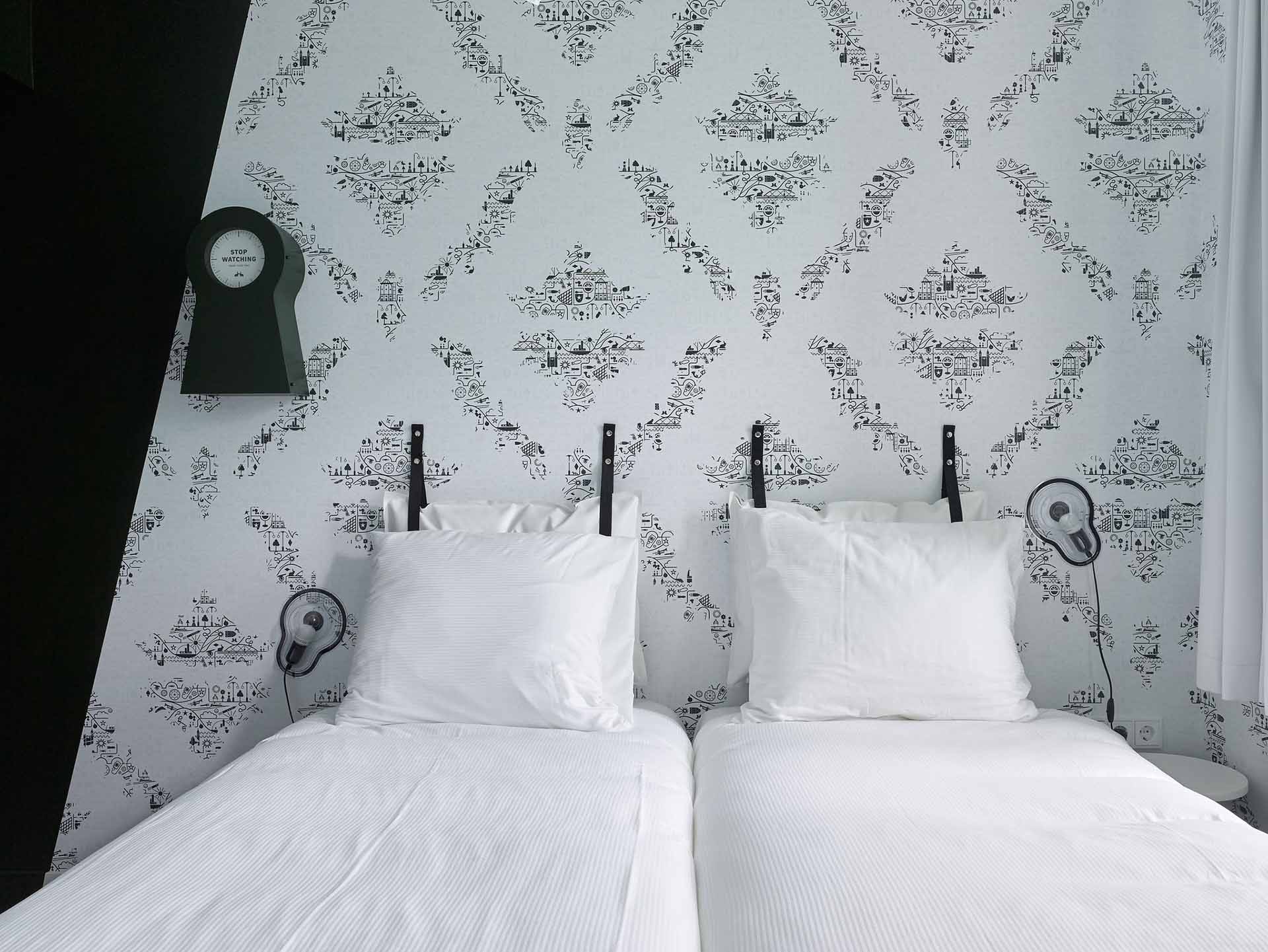 Helles Zimmer mit Doppelbett und Lampen an den Seiten | Kaboom-Hotel