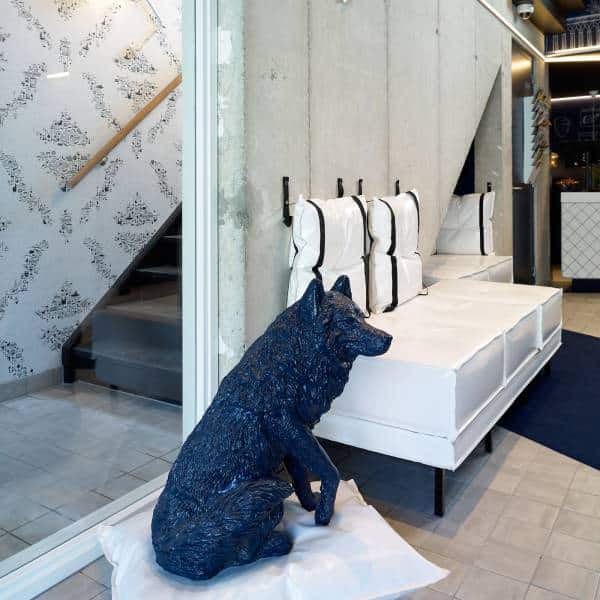 Lobby van Hotel Kaboom met blauw hondenfiguur en witte banken | Kaboom Hotel