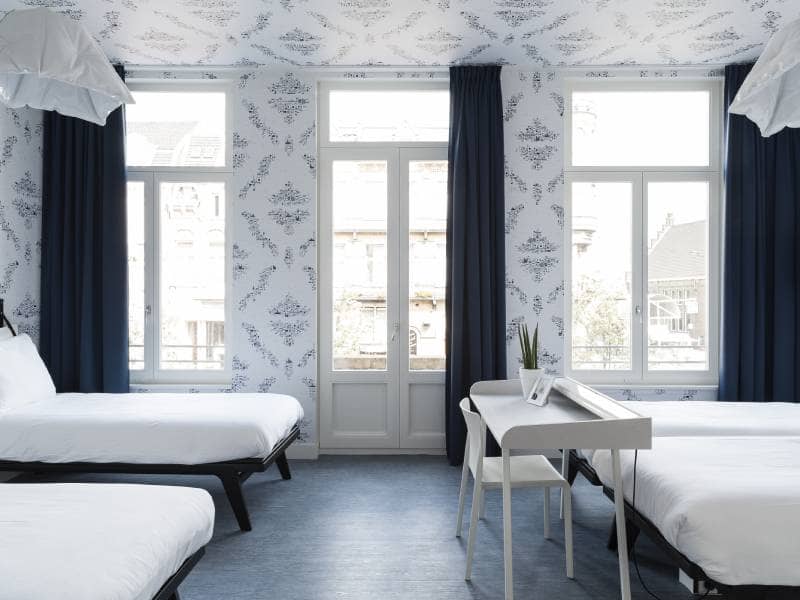 Lichte kamer met een tweepersoonsbed en twee eenpersoonsbedden en een bureau | Kaboom Hotel