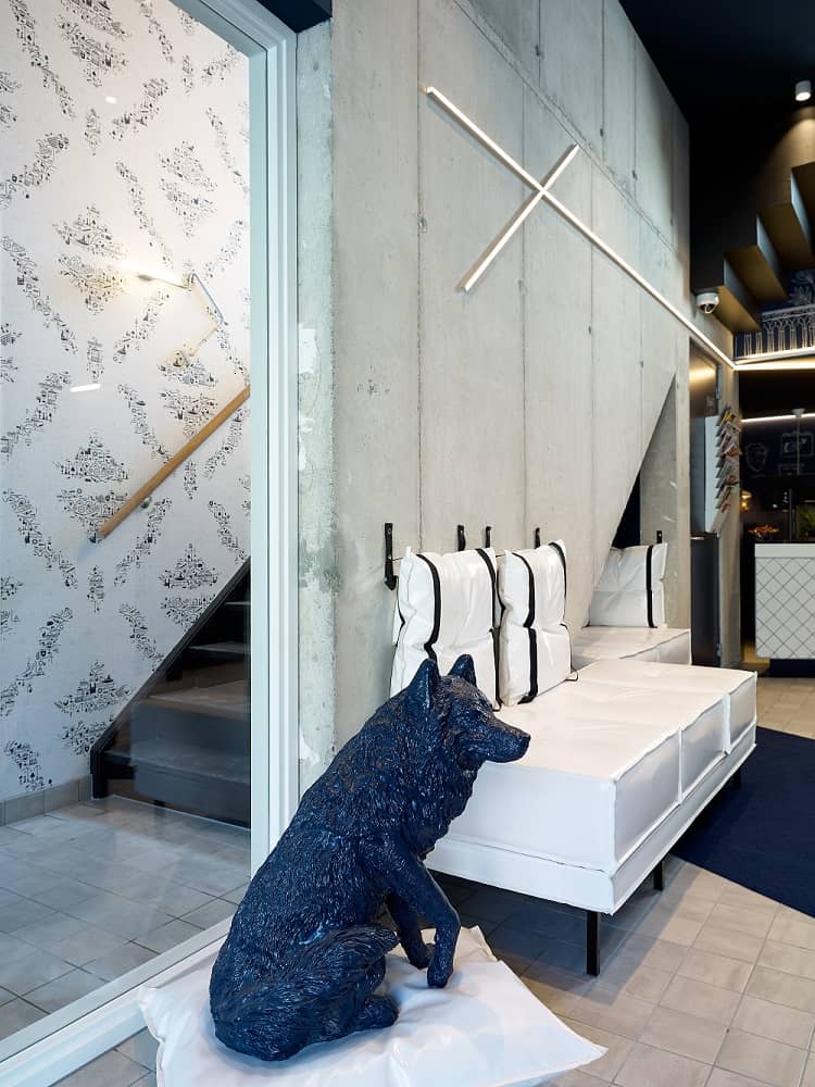 Lobby van Hotel Kaboom met blauwe hondenfiguur en witte banken | Kaboom Hotel