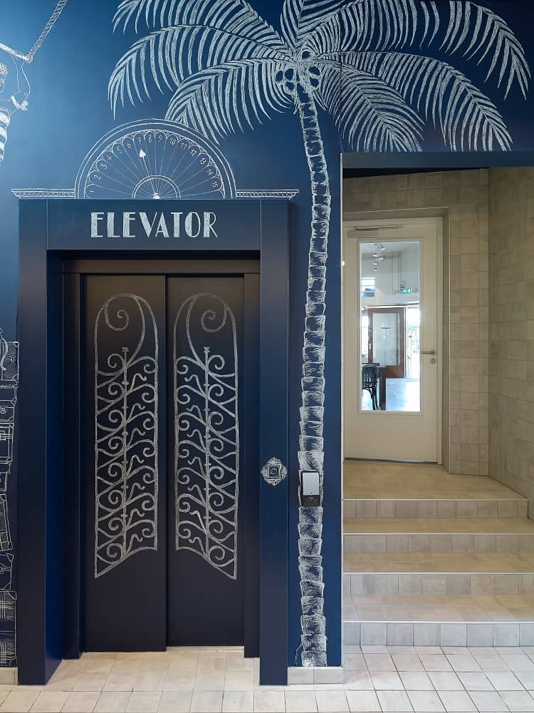 Blauwe lift naast trap in de lobby van het Kaboom Hotel