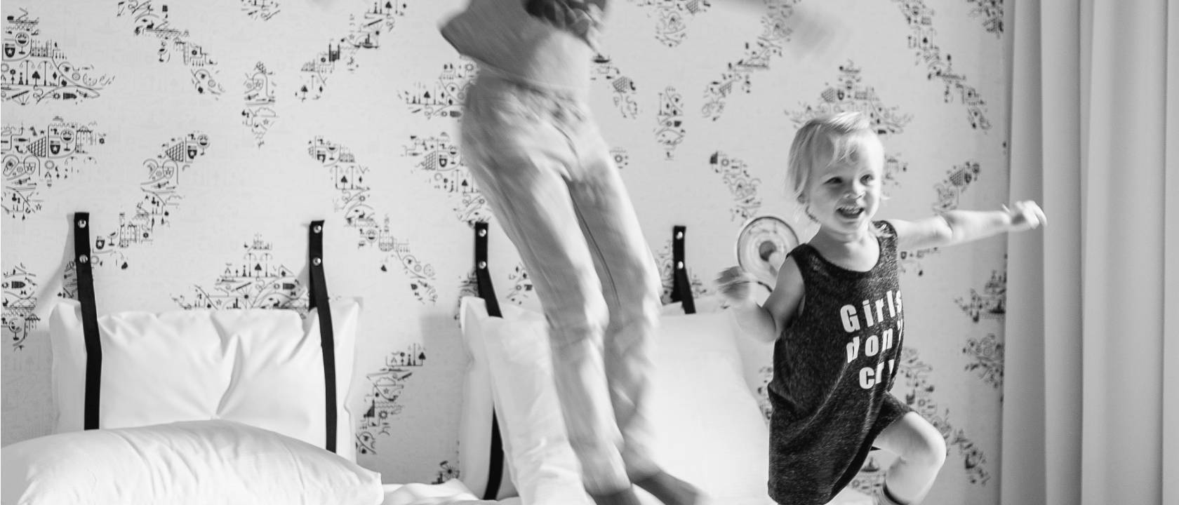 children jumping on a hotel bed in black and white | Kaboom Hotel